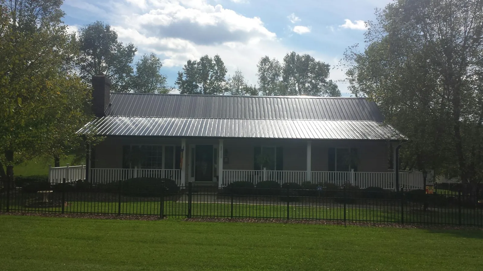 Gray metal roof on a brick ranch with a full width front porch — Gutter Guard Installation work by our crew in Livingston